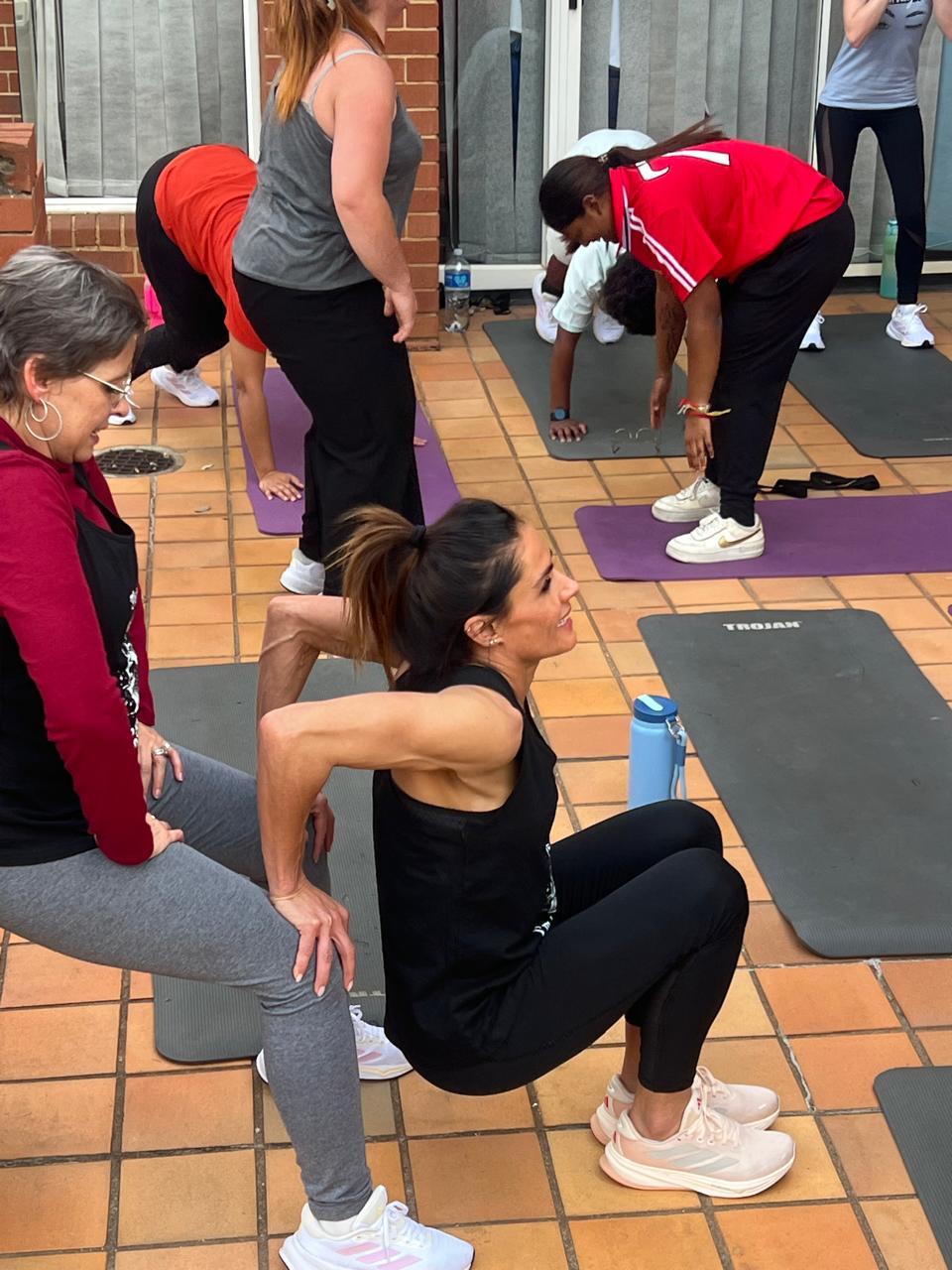 A coach guiding employees through an outdoor mobility and stretch session