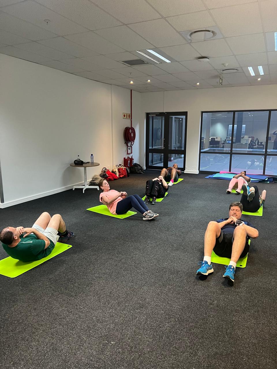 A full office floor of employees exercising on mats during a group class