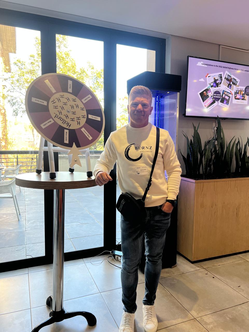 Brett Crowe next to a branded prize wheel at a corporate engagement activation